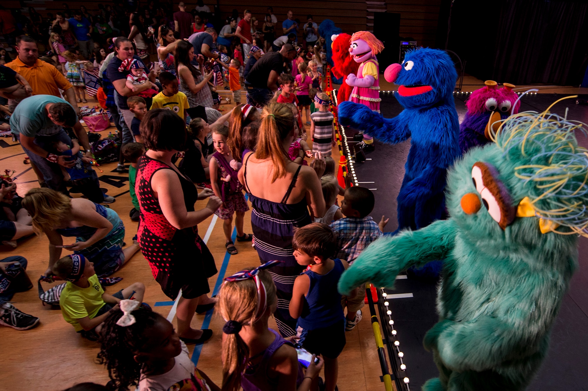 Characters from Sesame Street interact with military families at the end of a show for the 2015 Sesame Street/USO Experience for Military Families tour, inside the Skelton Memorial Fitness Center July 11, 2015, at Spangdahlem Air Base, Germany. Tour actors gave two performances based on the experiences military children. (U.S. Air Force photo by Senior Airman Rusty Frank/Released)