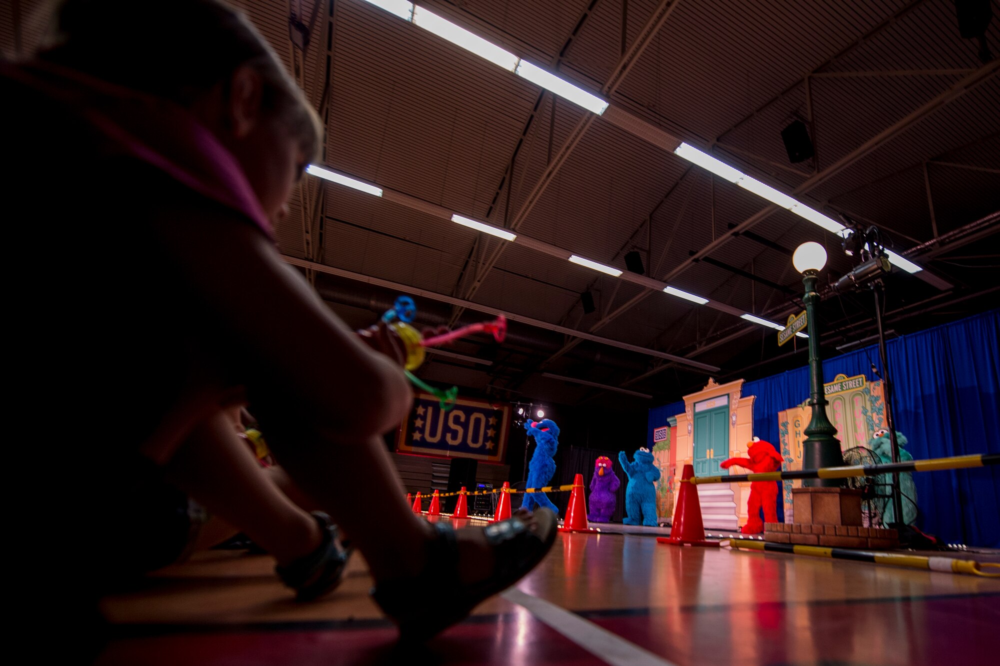 Military Children watch characters from Sesame Street perform for a show during the 2015 Sesame Street/USO Experience for Military Families tour, inside the Skelton Memorial Fitness Center July 11, 2015, at Spangdahlem Air Base, Germany. The show featured Sesame Street characters including Elmo, Cookie Monster and Rosita who sang danced about experiences of a military child. (U.S. Air Force photo by Senior Airman Rusty Frank/Released)
