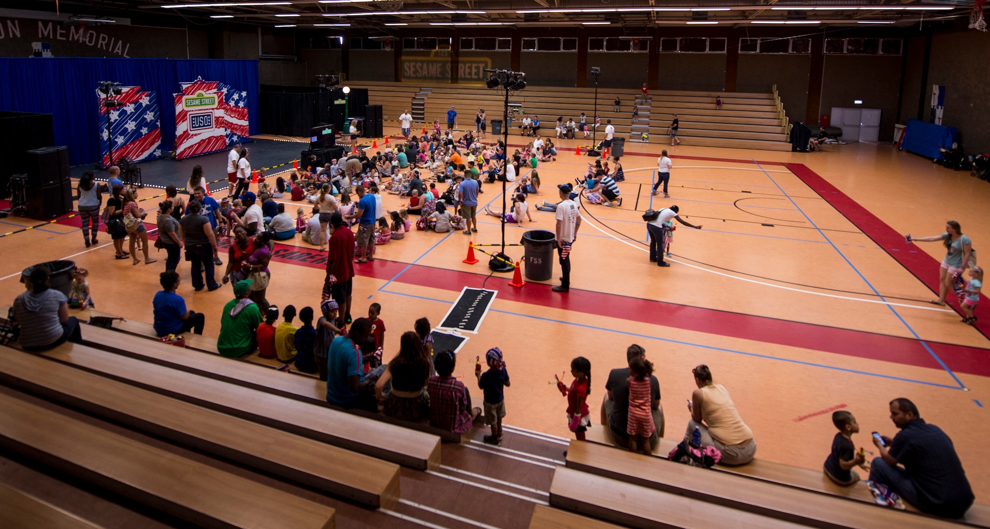 Military Families get ready for a show during the 2015 Sesame Street/USO Experience for Military Families tour, inside the Skelton Memorial Fitness Center July 11, 2015, at Spangdahlem Air Base, Germany. The USO and Sesame Street created a new character for the show named Katie, based off of the experiences of military children. (U.S. Air Force photo by Senior Airman Rusty Frank/Released)