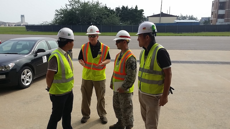 Chris Martin, (2nd from left) discusses quality control issues with contractors outside a job site on Kunsan Air Base.