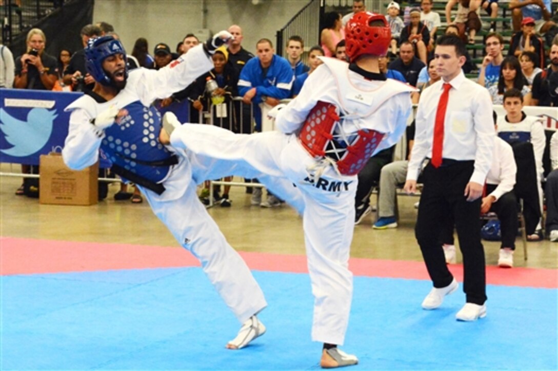 Army 1st Lt. Joshua Fletcher, center, scores a kick to his opponent's body during a match at the 2015 USA Taekwondo National Championships in Austin, Texas, July 8, 2015.