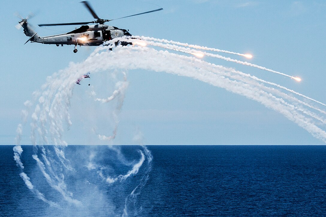An MH-60R Seahawk helicopter fires flares near the aircraft carrier USS Carl Vinson during an air power demonstration in the Pacific Ocean, July 11, 2015. The carrier hosted more than 2,000 family members and friends to demonstrate the ship's capabilities. The helicopter is assigned to Helicopter Maritime Strike Squadron 73.