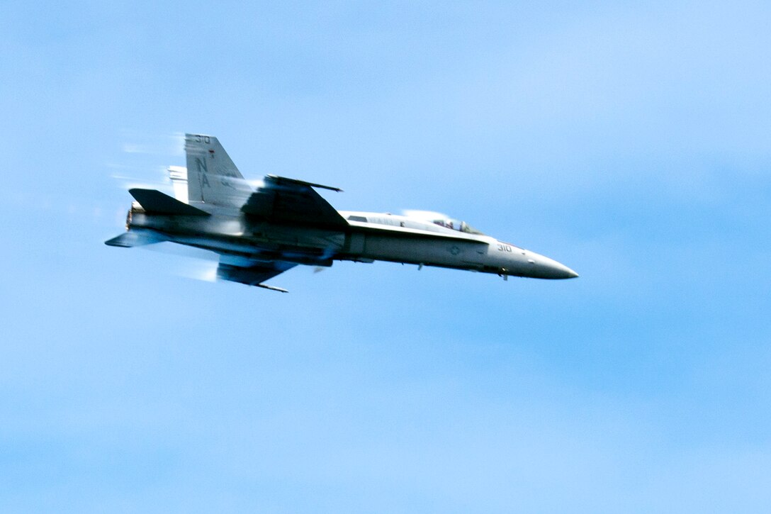 A F/A-18C Hornet assigned to Strike Fighter Squadron 113 flies past the aircraft carrier USS Carl Vinson in the Pacific Ocean, July 11, 2015.