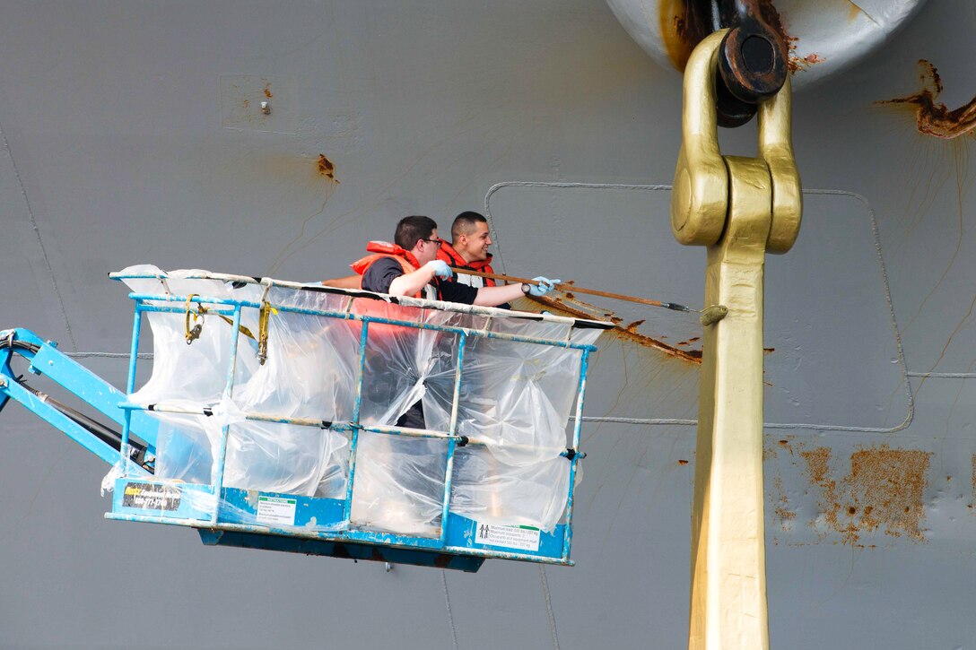 U.S. Navy Seaman Alexander Underwood and U.S. Navy Petty Officer 3rd Class David Del Rio paint the starboard anchor of the USS John C. Stennis in the Pacific Ocean, July 8, 2015. Underwood and Del Rio are boatswain's mates.