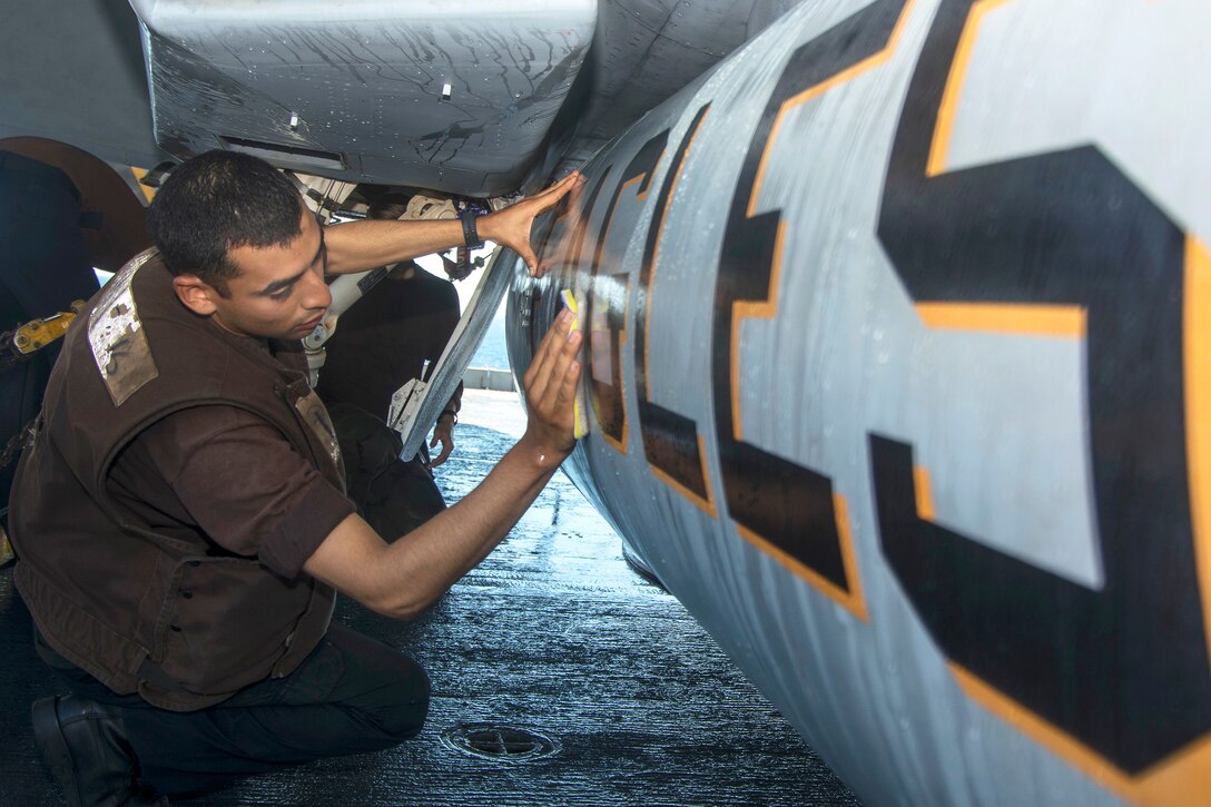 U.S. Navy Seaman John Guerrero cleans the fuel tank of an F/A-18E Super Hornet from Strike Fighter Squadron 115 on the flight deck of the Nimitz-class aircraft carrier USS George Washington in the Molucca Sea, July 4, 2015.