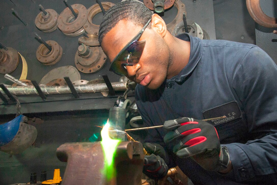 U.S. Navy Seaman Tarikh Williams brazes a pipe fitting aboard the Nimitz-class aircraft carrier USS George Washington in the Philippine Sea, July 3, 2015. Williams is an hull maintenance technician fireman.