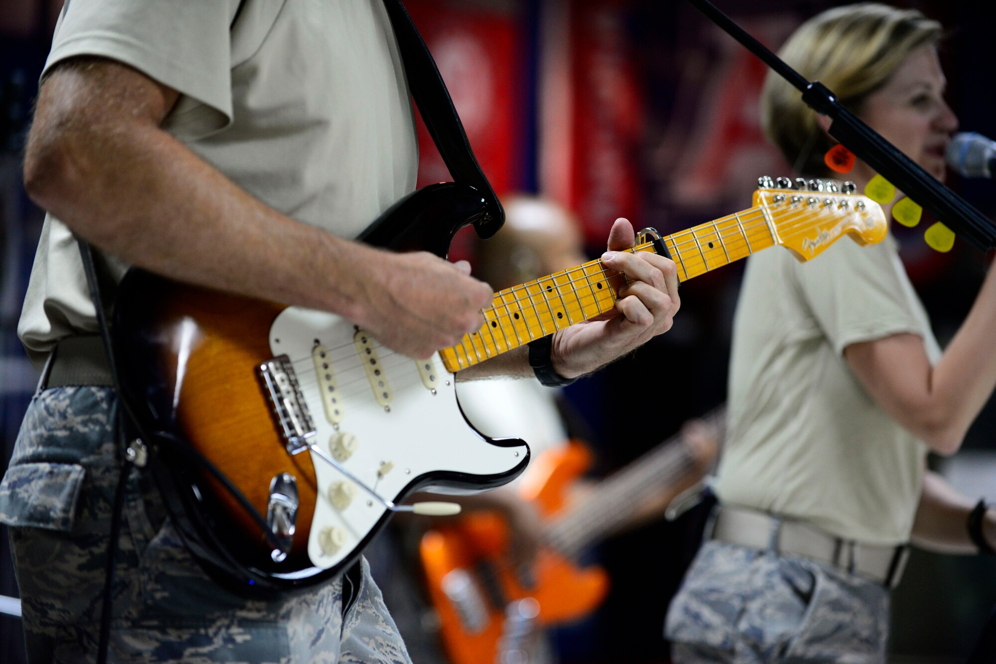 U.S. Air Force Staff Sgt. Darran Keenom, Air Forces Central Command band vocalist, guitarist and harmonica player, strums a guitar during a performance at an undisclosed location in Southwest Asia, July 6, 2015. The band played several genres of music to appeal to all ages. (U.S. Air Force photo by Senior Airman Racheal E. Watson/Released)