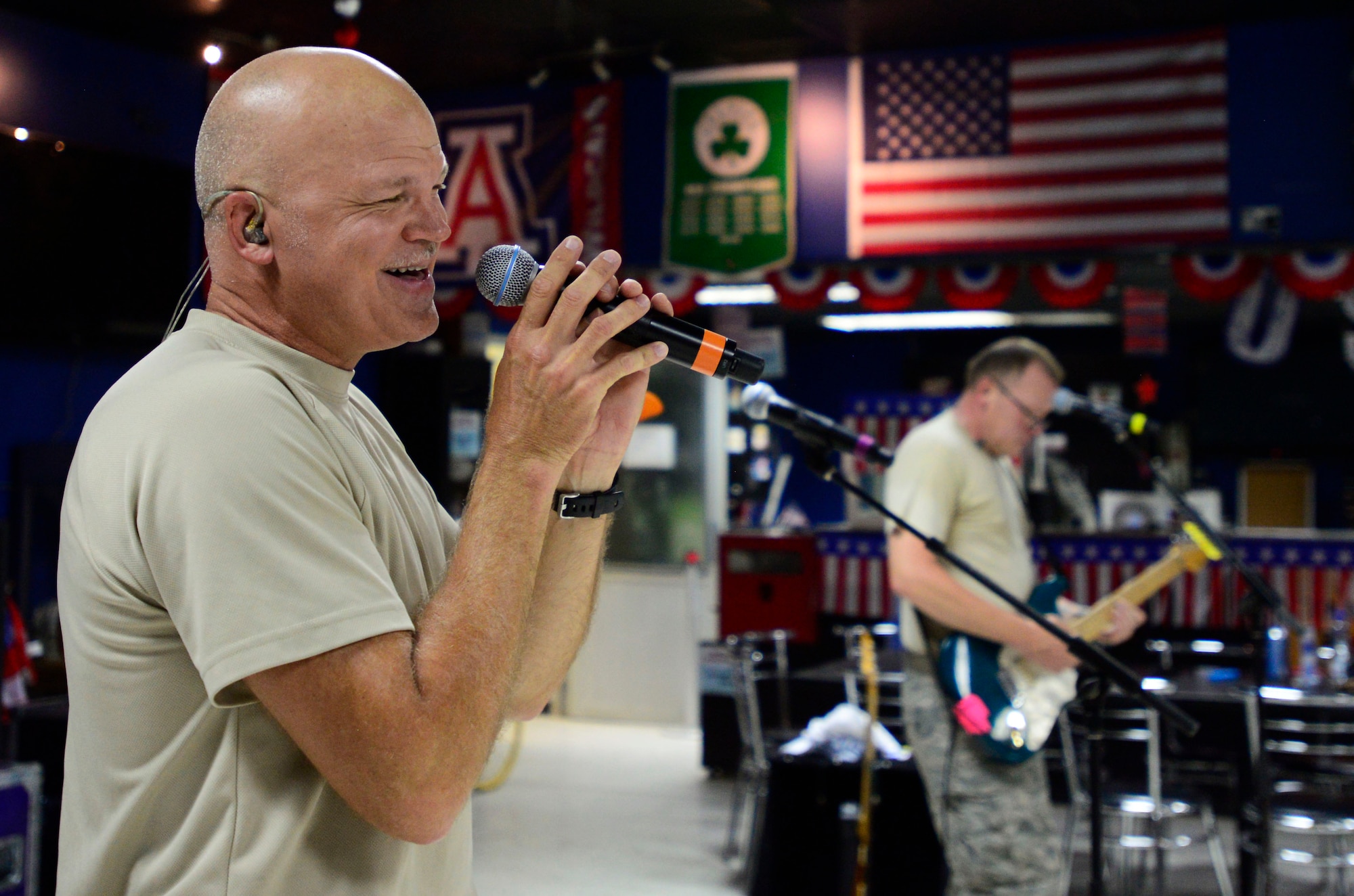 U.S. Air Force Staff Sgt. Darran Keenom, Air Forces Central Command band vocalist, guitarist and harmonica player, sings during a performance at an undisclosed location in Southwest Asia, July 6, 2015. The band is composed of musicians who perform and tour throughout the area of responsibility to encourage troop morale, diplomacy and outreach to host nation communities. (U.S. Air Force photo by Senior Airman Racheal E. Watson/Released)