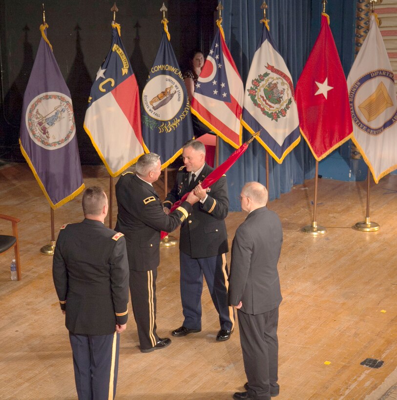 Col. Philip Secrist receives the Corps flag from Brig, Gen. Richard Kaiser, Commanding General, Great Lakes and Ohio River Division, formally taking command of the Huntington District at a Change of Command Ceremony held at the Huntington City Hall Auditorium July 10, 2015. Outgoing commander, Col. Leon Parrott looks on.
