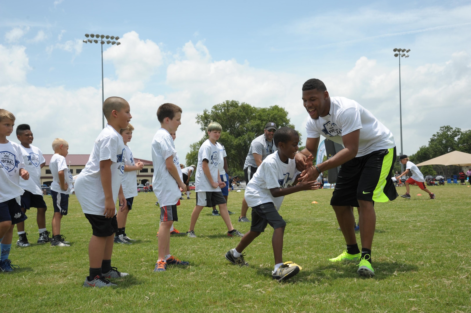 Terrance Williams, Dallas Cowboy wide receiver, instructs children during a youth football camp July 7 at Joint Base San Antonio-Randolph. Throughout the camp, Williams offered tips and instruction, highlighting the finer points of football. Campers experienced various stations specializing in fundamental skills and participated in touch football games. (U.S. Air Force photo by Joel Martinez/Released)