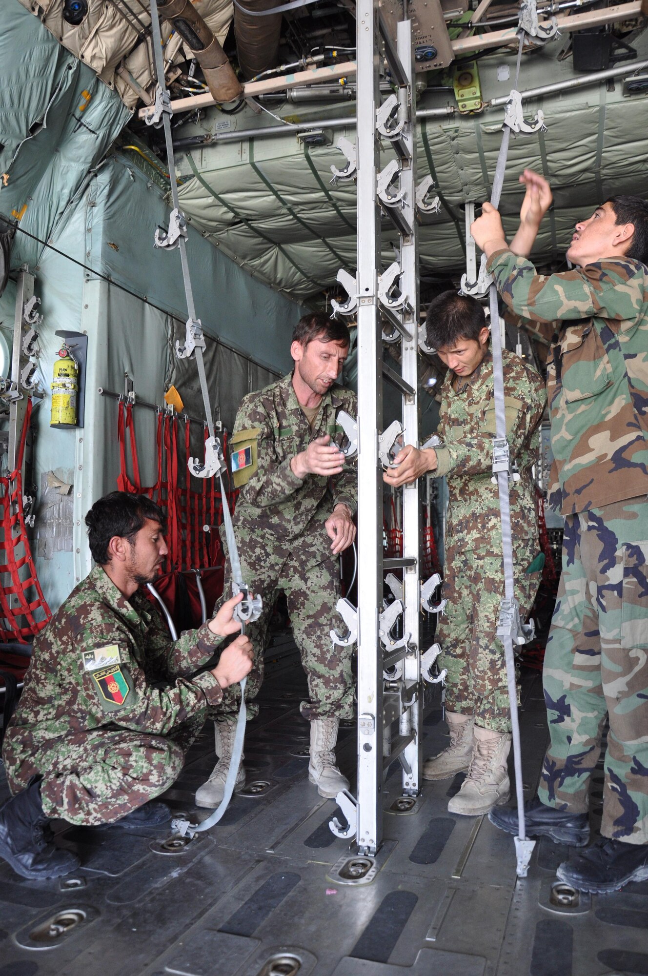 Four Afghan National Army flight medics work as a team to reconfigure the cargo compartment of a C-130H Hercules from netted seating to metal stanchions that hold stretchers for a “simulated” medical evacuation, or medevac, flight at Hamid Karzai International Airport, July 9, 2015. The Train, Advise, Assist Command – Air (TAAC-Air) advisers provide weekly training to the ANA and Afghan air force to further develop and grow their fight medics. (U.S. Air Force photo/Capt. Eydie Sakura/released)