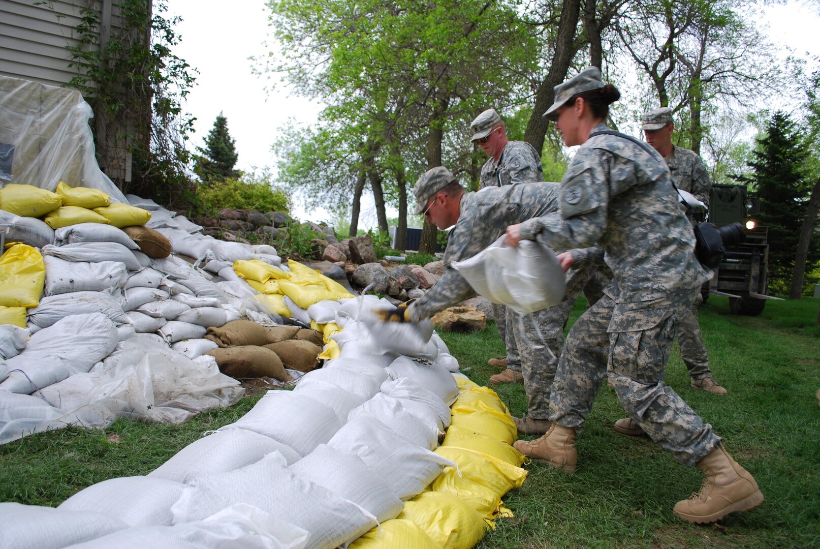 Spc. Kerry B. Thompson (from foreground), of Bismarck; Spc. Jacob Knain, of Rugby, and Staff Sgt. Jesse Walstad, of Bismarck, help build a sandbag dike at a house along Nordic Lane in Bismarck, N.D., June 2, 2011. The North Dakota National Guard Soldiers serve with the Bismarck-based 957th Engineer Company (Multi-Role Bridge) and the 814th Medical Company (Area Support) and are spread out throughout the Bismarck and Mandan communities to help hold back the rising Missouri River. (Photo by Staff Sgt. Amy Wieser Willson, North Dakota National Guard Public Affairs Office)
