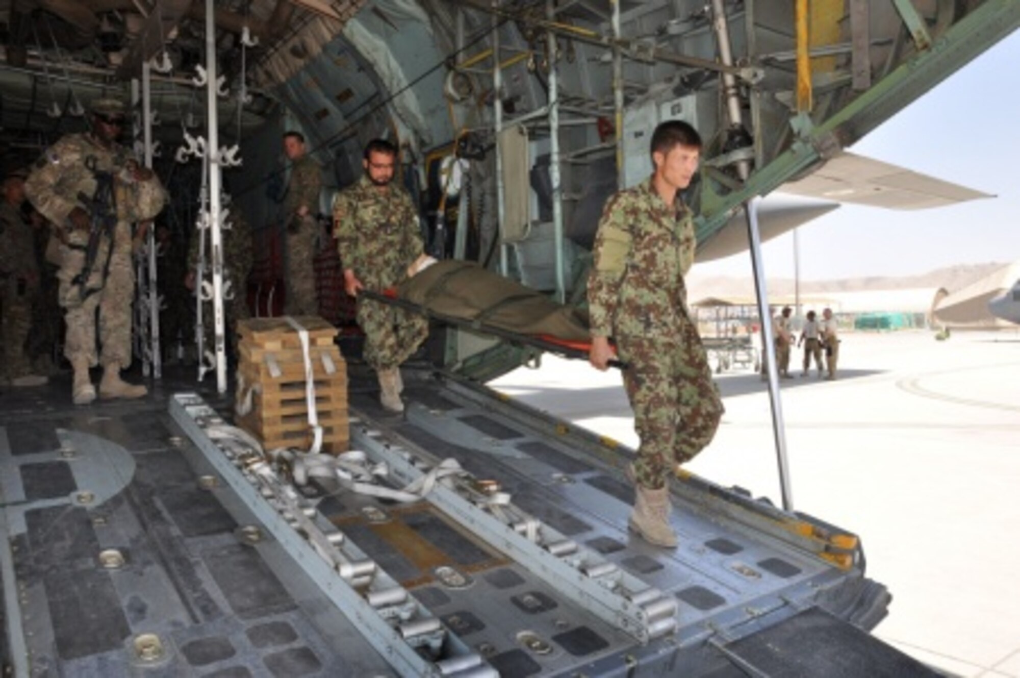 Two Afghan National Army flight medics carry a litter, or stretcher, from the back of a C-130H Hercules during a simulated medical evacuation flight at Hamid Karzai International Airport, Afghanistan, July 9, 2015. The Train, Advise, Assist Command - Air (TAAC-Air) advisors provide weekly training to the ANA and Afghan air force to further develop and grow their fight medics’ capabilities. (U.S. Air Force photo/Capt. Eydie Sakura)