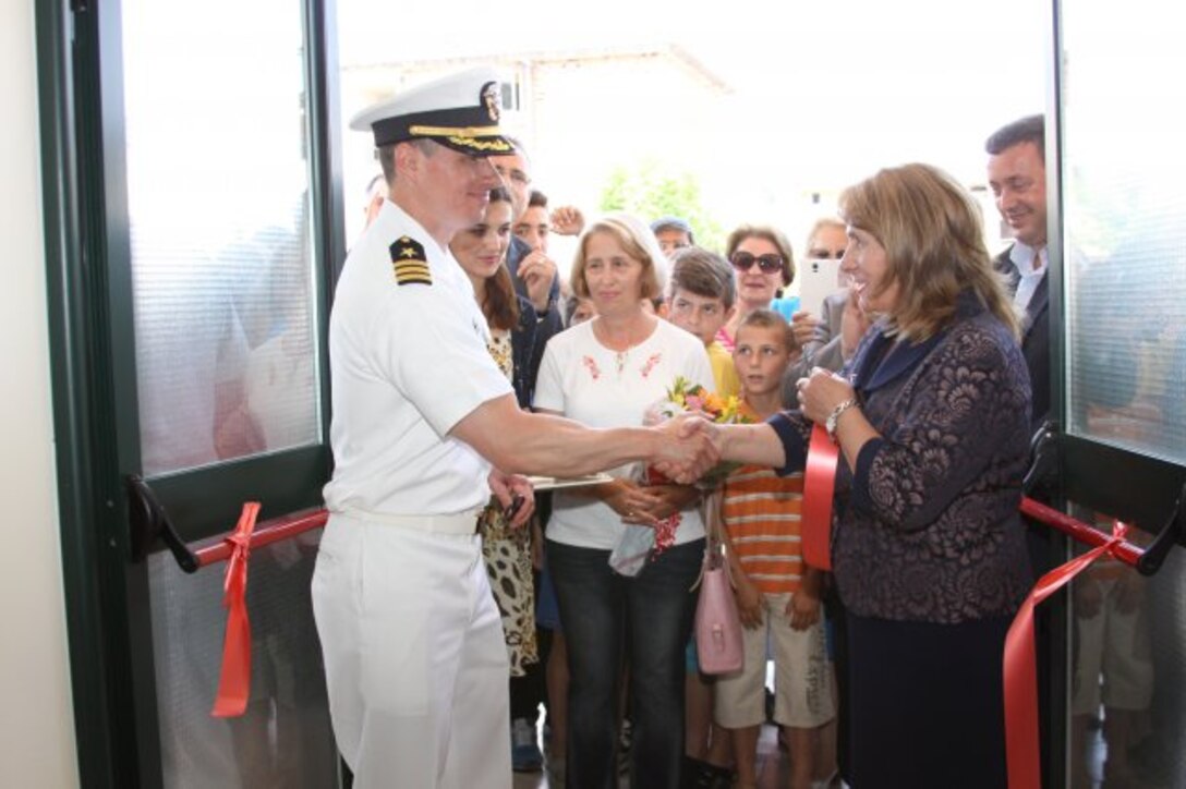 Navy Cmdr. Ralph Shield, U.S. Embassy Tirana's defense attaché, shakes hands with school director Mjaftoni Dhimitri after the ribbon-cutting ceremony June 11 for "28 Nentori," a local nine-year school in Kucove, Albania.