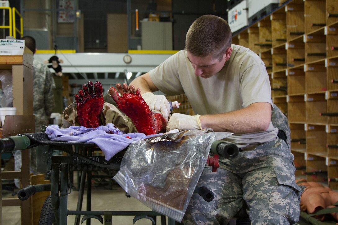 U.S. Army Pfc. Alex Campbell, a resident of Midlothian, Texas, and a member of the 94th Combat Support Hospital, 807th Medical Command, tinkers with a bloody shin on a medical mannequin during the 2015 Global Medic Exercise at Fort McCoy, Wis., June 15, 2015. Global Medic is a joint and combined exercise that gives Army Reserve Soldiers the opportunity to practice their medical skills in a mobile hospital environment with members of the U.S. Navy, U.S. Air Force and the British army reserve. (U.S. Army Photo by Sgt. 1st Class Adam Stone)