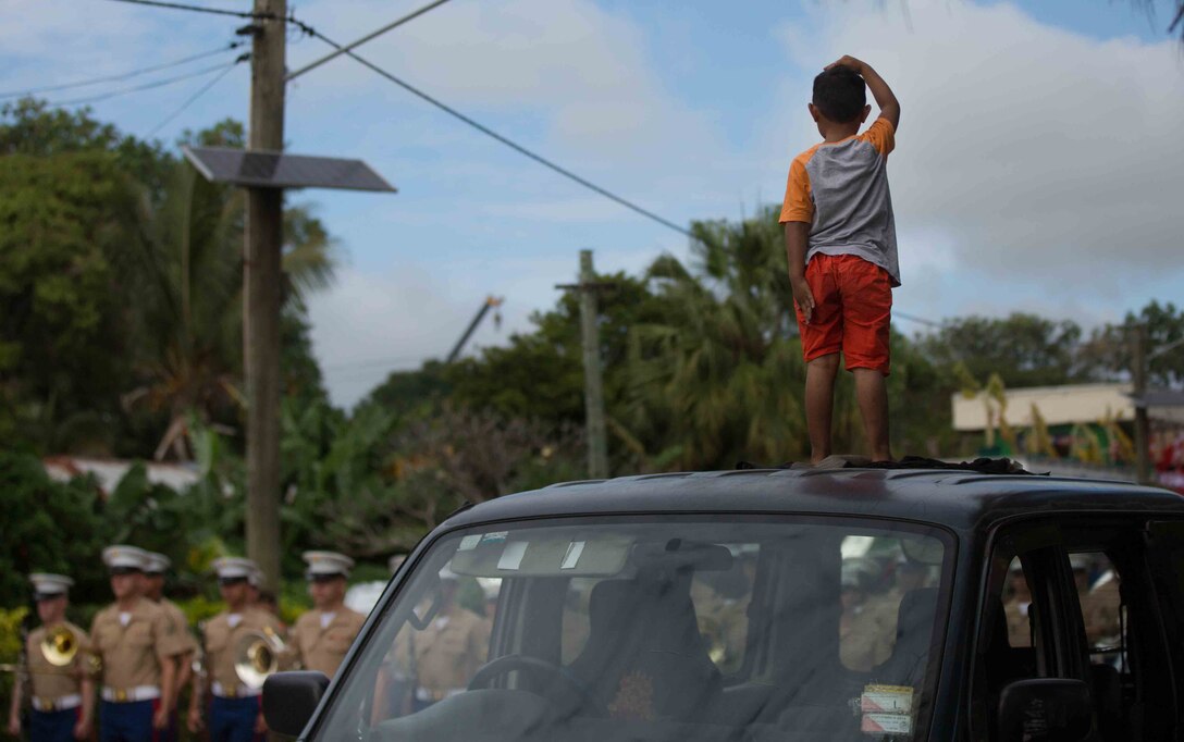 A Tongan boy salutes the U.S. Marine Corps Forces, Pacific Band as they march in a celebration parade in Nukua'lofa, Tonga, July 8, 2015. The U.S. Marine Corps Forces, Pacific Band plays an integral role in promoting an understanding of other cultures and recognizing the importance of the arts as a bridge between people. (U.S. Marine Corps photo by Cpl. Brittney Vito/Released)