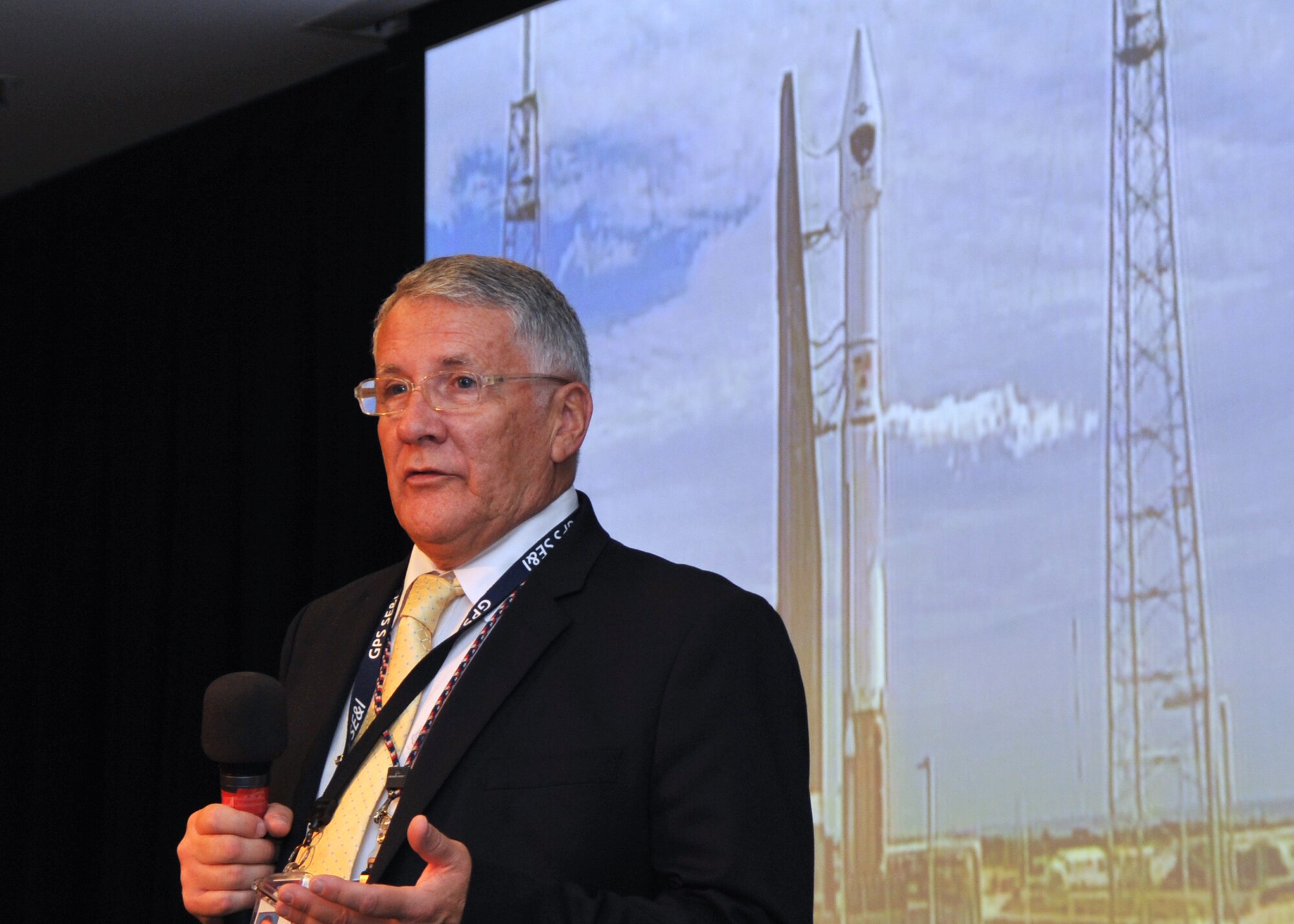 With a United Launch Alliance Atlas V launch vehicle in the background, R. Bruce Lagatree, GPS System Engineering and Integration Program principal systems engineer for Leidos, previously known as Science Applications International Corporation briefs an audience of more than 150 SMC personnel in the Gordon Conference Center at Los Angeles Air Force Base in El Segundo, Calif. On July 15, 2015, a ULA Atlas V in the “401” vehicle configuration of a four-meter-wide payload fairing, zero solid rocket boosters and a single engine upper stage successfully carried a GPS IIF-10 satellite into orbit at 11:36 a.m. EDT from Launch Complex 41 at Cape Canaveral Air Force Station in Florida for the Global Positioning System navigation network. (U.S. Air Force photo/Sarah Corrice)