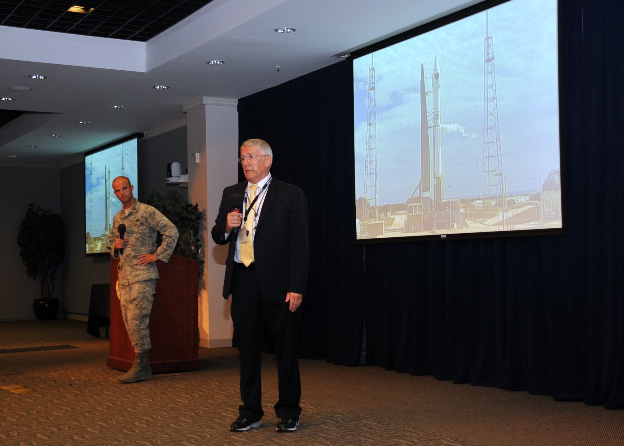 R. Bruce Lagatree, GPS System Engineering and Integration Program principal systems engineer for Leidos, previously known as Science Applications International Corporation and Capt. Nick Laliberte, Government Mission Integration Manager from the Space and Missile Systems Center’s Launch Systems Directorate briefs an audience of more than 150 SMC personnel in the Gordon Conference Center at Los Angeles Air Force Base in El Segundo, Calif. On July 15, 2015, a United Launch Alliance Atlas V in the “401” vehicle configuration of a four-meter-wide payload fairing, zero solid rocket boosters and a single engine upper stage successfully carried a GPS IIF-10 satellite into orbit at 11:36 a.m. EDT from Launch Complex 41 at Cape Canaveral Air Force Station in Florida for the Global Positioning System navigation network. (U.S. Air Force photo/Sarah Corrice)