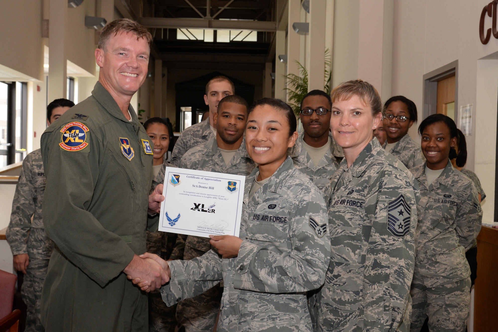 Senior Airman Denise Hill, center, 47th Force Support Squadron career development journeyman, poses with Col. Thomas Shank, 47th Flying Training Wing commander, and Chief Master Sgt. Teresa Clapper, 47th FTW command chief, after accepting the XLer of the Week award, here, July 9, 2015. The XLer is a weekly award chosen by wing leadership and is presented to those who consistently make outstanding contributions to their unit and Laughlin. (U.S. Air Force photo by Airman 1st Class Brandon May)