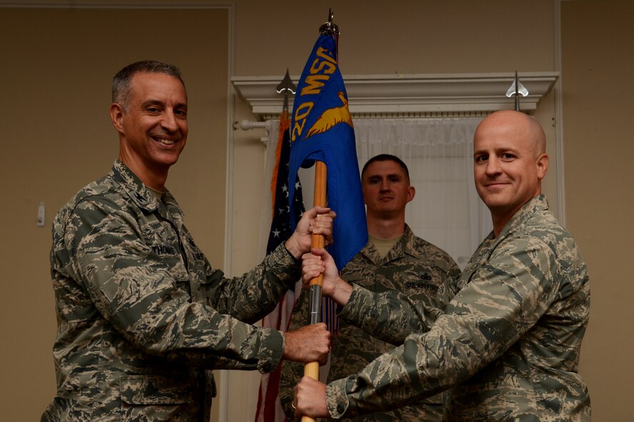 U.S. Air Force Lt. Col. David McCoy, outgoing 20th Communications Squadron commander, passes the unit guidon to Col. John Thomas, 20th Mission Support Group commander, during the 20th CS change of command ceremony at Shaw Air Force Base, S.C., July 15, 2015. The passing of a guidon represents the effective change in leadership within a unit. (U.S. Air Force photo by Senior Airman Jonathan Bass/Released)