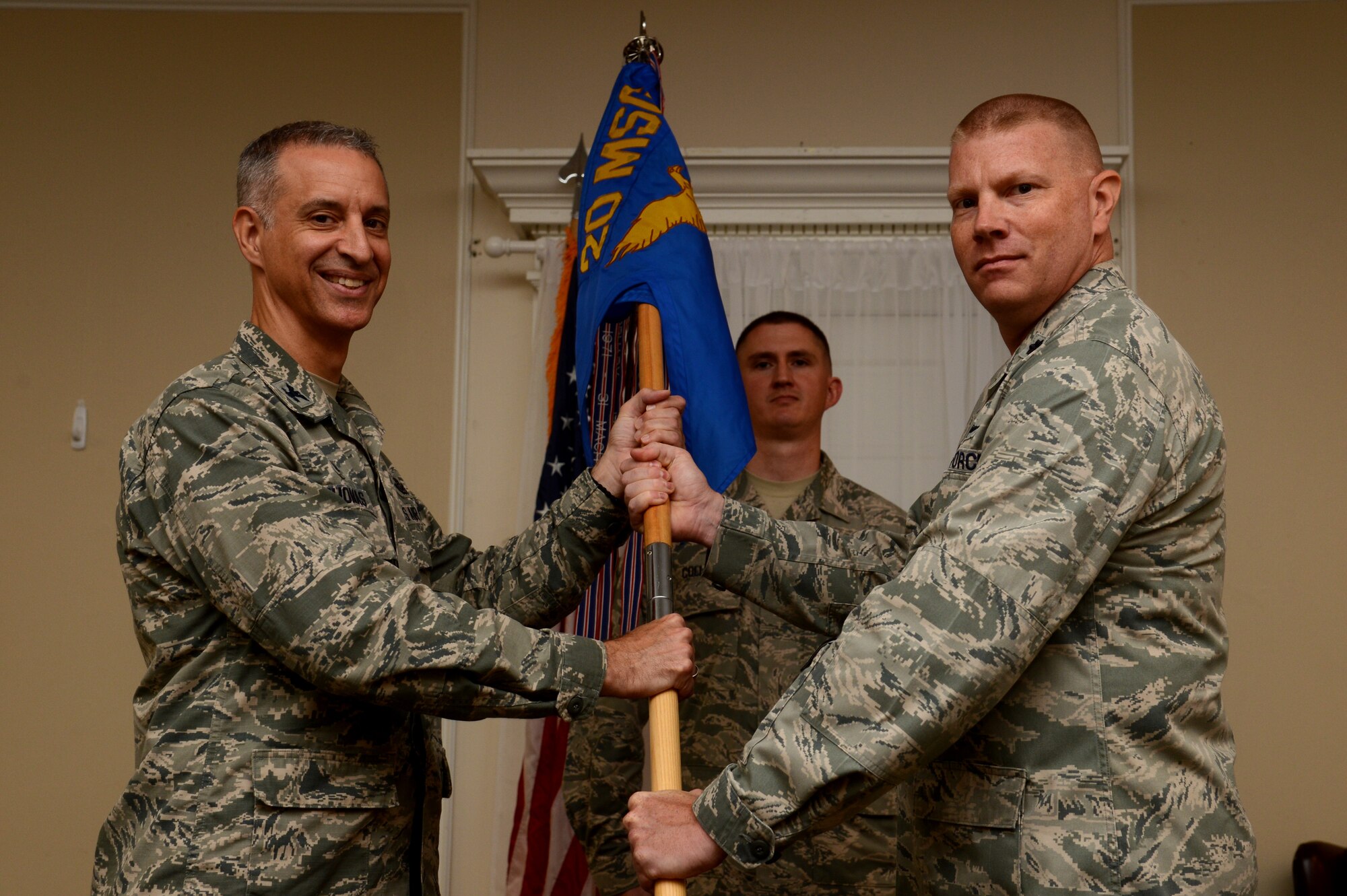 U.S. Air Force Lt. Col. David McCoy, outgoing 20th Communications Squadron commander, passes the unit guidon to Col. John Thomas, 20th Mission Support Group commander, during the 20th CS change of command ceremony at Shaw Air Force Base, S.C., July 15, 2015. The passing of a guidon represents the effective change in leadership within a unit. (U.S. Air Force photo by Senior Airman Jonathan Bass/Released)