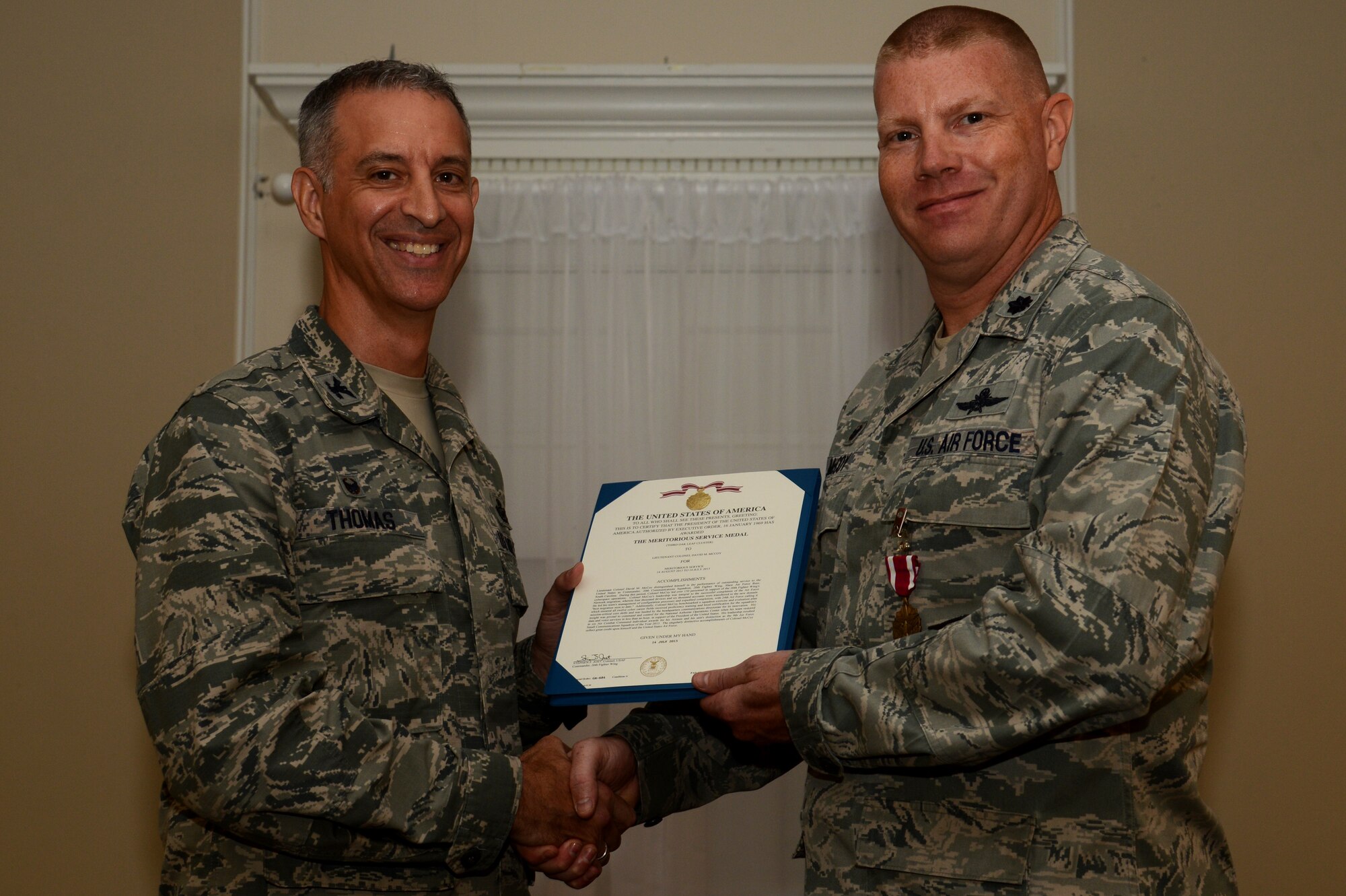 U.S. Air Force Lt. Col. David McCoy, outgoing 20th Communications Squadron commander, receives the Meritorious Service Medal from Col. John Thomas, 20th Mission Support Group commander, during the 20th CS change of command ceremony at Shaw Air Force Base, S.C., July 15, 2015. The 20th CS provides superior communications, mission-ready cyber capabilities and support forces to enable command and control for Team Shaw and worldwide operations. (U.S. Air Force photo by Senior Airman Jonathan Bass/Released)