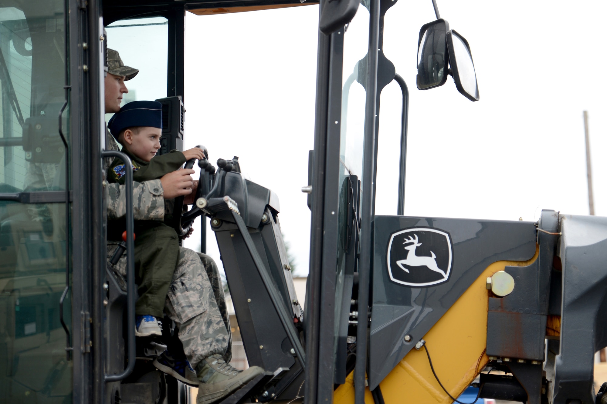 Ewan McFadgen, Pilot for a Day, controls a road grader with the help of Staff Sgt. Joseph Farrell, 627th Civil Engineer Squadron equipment and pavement craftsman, July 10, 2015, during his tour of Joint Base Lewis-McChord, Wash. McFadgen was able to operate and view demonstrations of some of the equipment that 627th CES Airmen use every day. (U.S. Air Force photo/Airman 1st Class Keoni Chavarria)