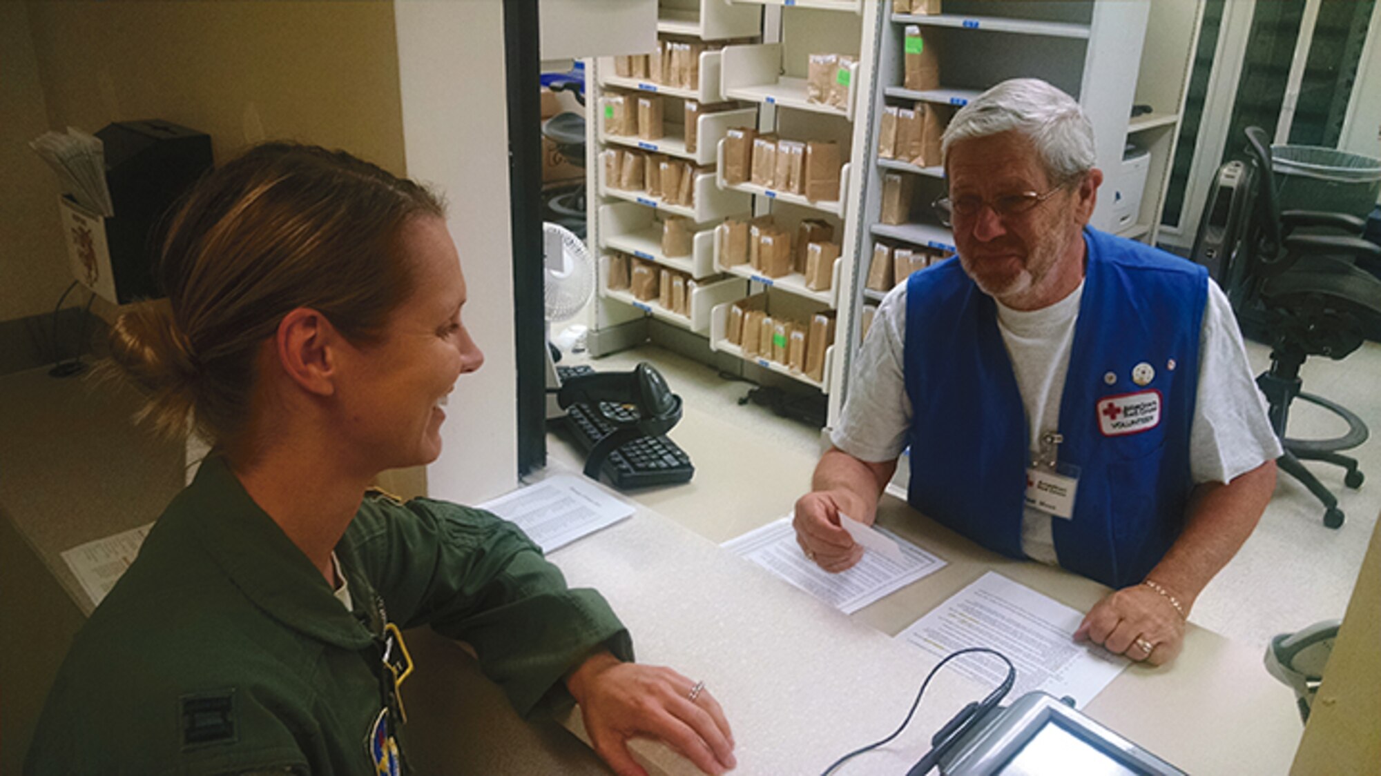Lee Moss, a Red Cross volunteer at the 377th Medical Group’s pharmacy, helps a customer. Moss has volunteered at the pharmacy for six years. (Photo by Ryan Stark)
