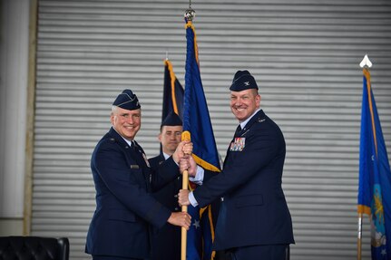 (Right) Gen. Frederick Martin, U.S. Air Force Expeditionary Center commander, passes the Joint Base Charleston guidon to Col. Robert Lyman during a change of command ceremony, July 14, 2015 at Joint Base Charleston – Air Base, S.C. Col. Jeffrey DeVore, outgoing commander, is heading to the Pentagon to become chief of the Global Mobility Division in Washington, D.C., working on the Headquarters Air Force staff. (U.S. Air Force photo/Senior Airman Jared Trimarchi)