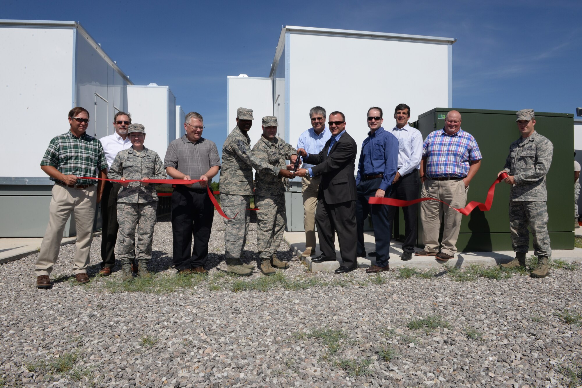 ALTUS AIR FORCE BASE, Okla. – U.S. Air Force Col. Todd Hohn, 97th Air Mobility Wing commander, and U.S. Air Force Chief MSgt. James Powell, 97th Air Mobility Wing command chief Master Sgt., cut a ribbon during the 9-megawatt interactive distributed generation system ribbon cutting ceremony, July 13. The $4 million generator system was given to Altus AFB by Western Farmers Electrical Cooperative after proving to be a mutually beneficial and reliable solution to mitigate any issues that may arise from the increasing necessity for electricity. (U.S. Air Force photo by Airman 1st Class Megan E. Acs/Released) 