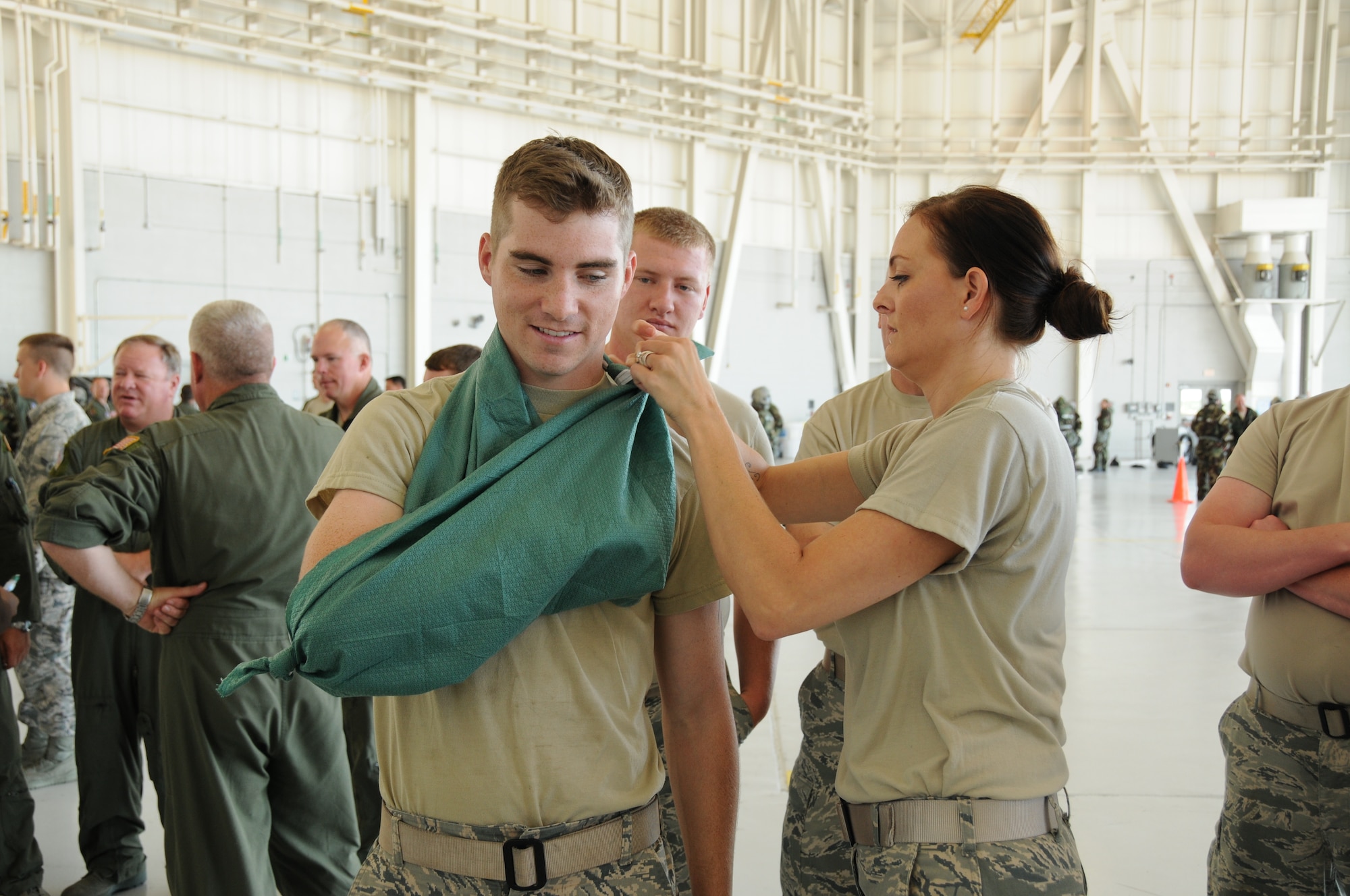 U.S. Air Force Tech. Sgt. Shanna Bufkin, 186th Air Refueling Wing Medical Group member, demonstrates how to tie a sling on Airman 1st Class Kyle Koch during the Expeditionary Skills Refresher Course at the Combat Readiness Training Center, Gulfport, Miss., July 14, 2015. The  refresher course included both Self-Aid Buddy Care and Chemical, Biological, Radiological, Nuclear and Explosives survival. (U.S. Air National Guard photo by Senior Airman Jessica Fielder/Released)