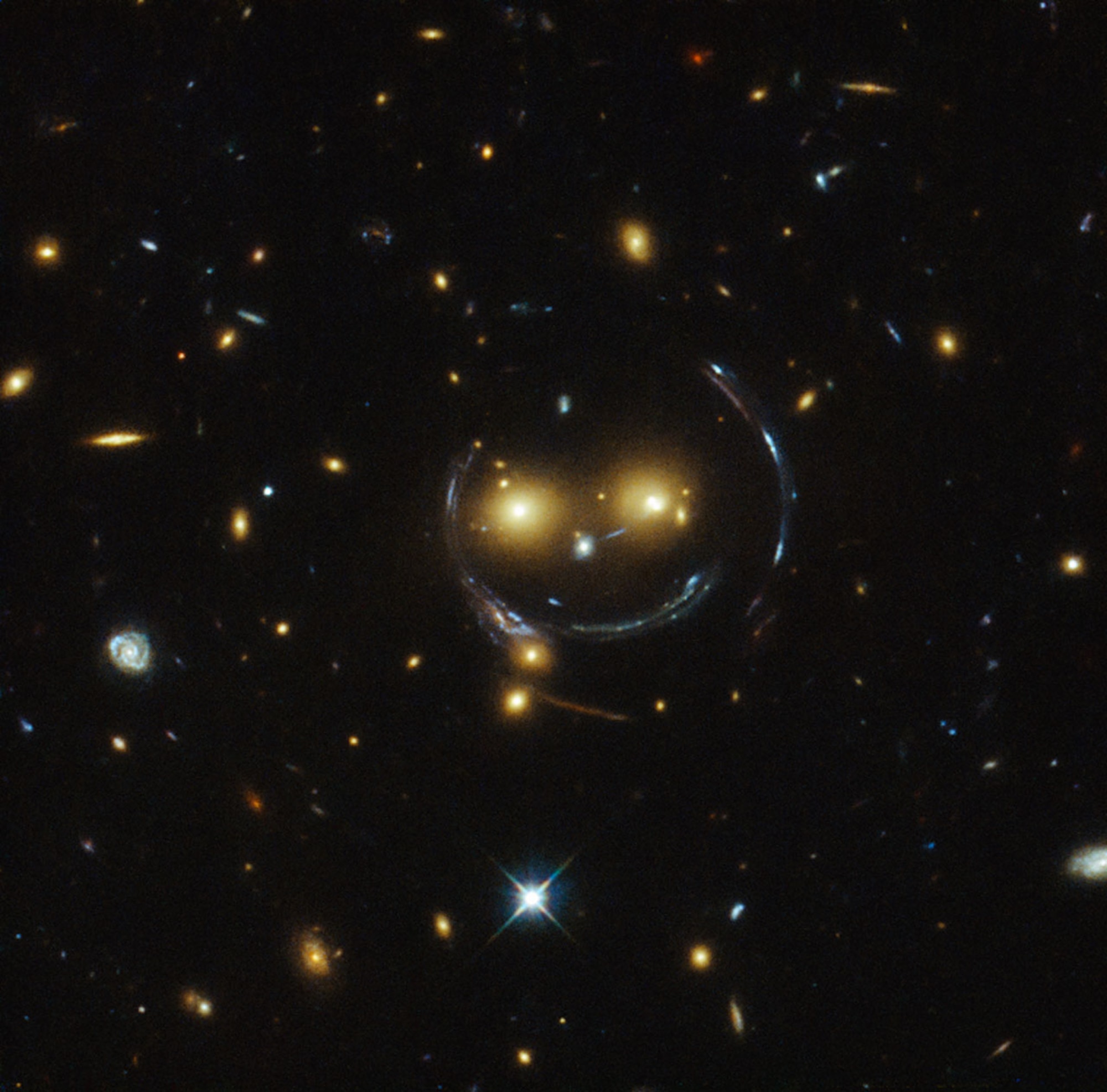 "Smiley" image of galaxy cluster and gravitational lensing (an Einstein ring). (Wikipedia photo)