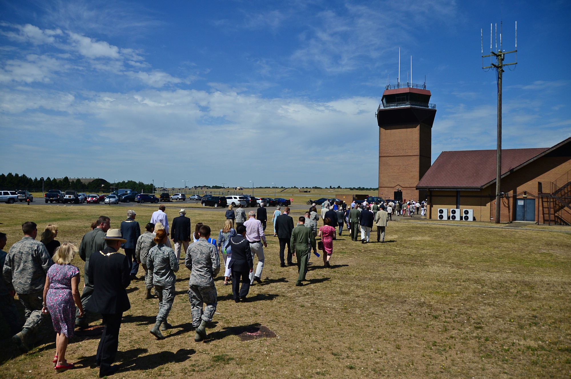 Airmen and local community leaders head towards a control tower to observe a display prepared for an Honorary Commanders summer reception at Royal Air Force Lakenheath, England, July 10, 2015. Attendees witnessed a birds of prey and military working dog demonstration and several unit displays, providing Airmen the opportunity to interact with key leaders and local British dignitaries. (U.S. Air Force photo by Senior Airman Erin O’Shea/Released) 