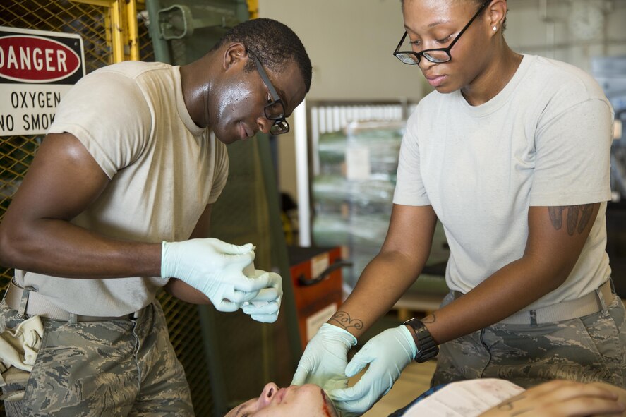 (Left to right) Airman 1st Class Anthony Tyson and Senior Airman Ashley Jones, both from the 374th Surgical Operations Squadron, treat a simulated casualty during an Emergency Management Exercise at Yokota Air Base, Japan, July 13, 2015. The EME trained Yokota for possible real-world situations requiring response and communication between on-base organizations. (U.S. Air Force photo by Osakabe Yasuo/Released)