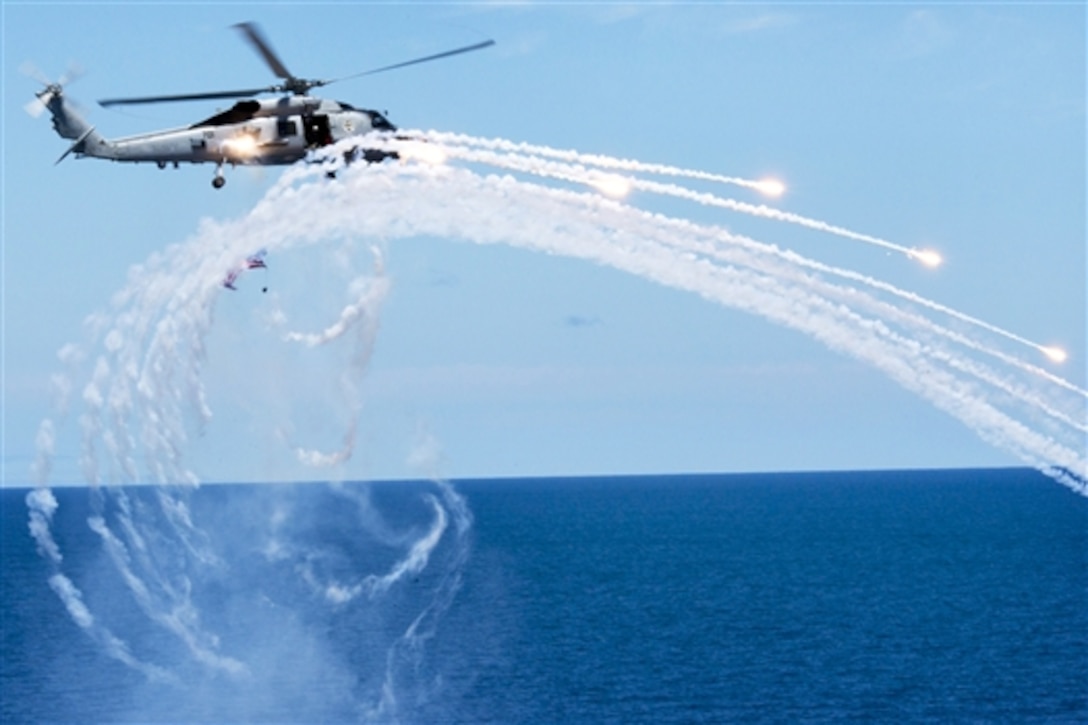 An MH-60R Seahawk helicopter fires flares near the aircraft carrier USS Carl Vinson during an air power demonstration in the Pacific Ocean, July 11, 2015. The carrier hosted more than 2,000 family members and friends to demonstrate the ship's capabilities. The helicopter is assigned to Helicopter Maritime Strike Squadron 73.