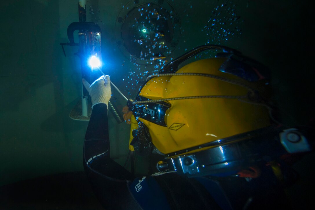 Navy Petty Officer 3rd Class Phil Wall makes a vertical weld on two half-inch pieces of steel during underwater training in Miami, Florida, July 13, 2015. Wall is a construction electrician assigned to Underwater Construction Team 2.