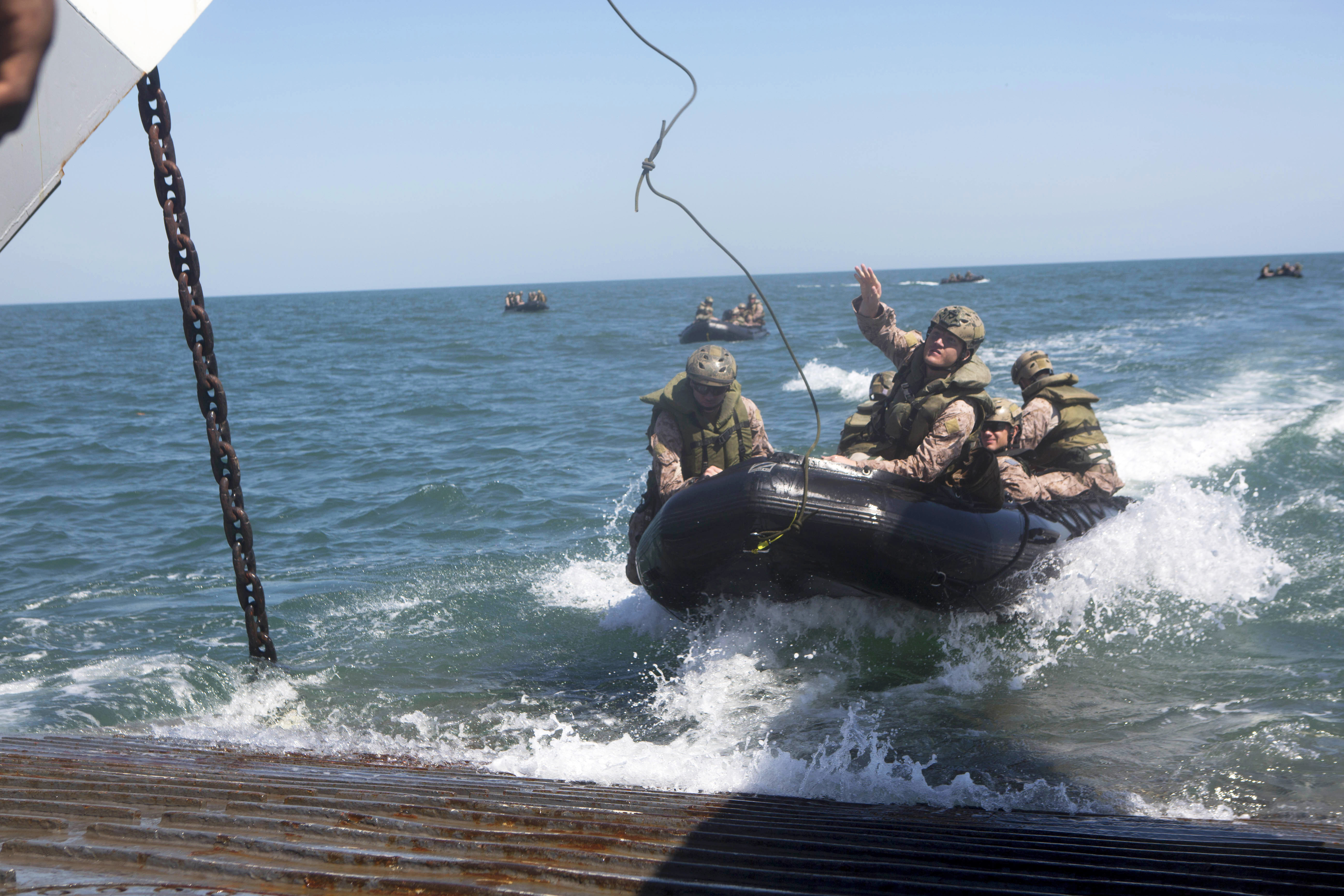 A U.S. Marine throws a rope as they approach a landing craft utility boat  during combat