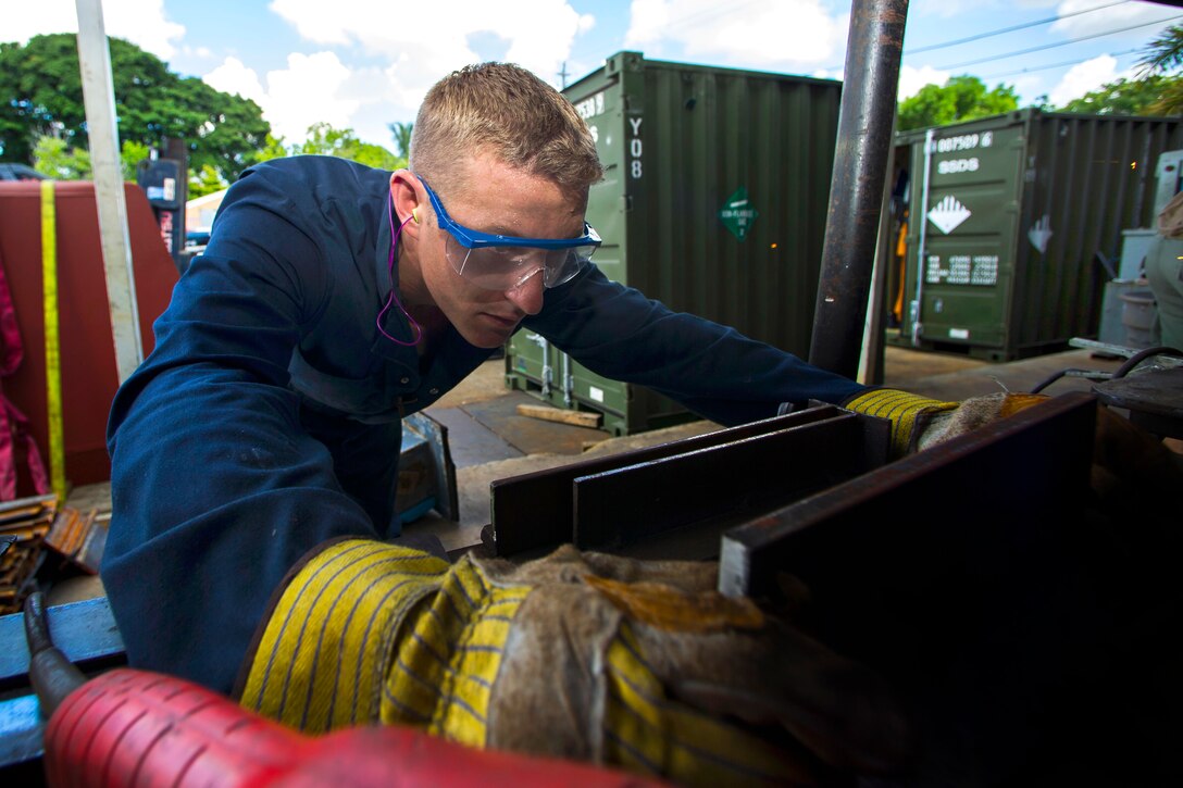 Navy Petty Officer 1st Class Jesse Hamblin checks for imperfections on the surface of a half-inch steel plate before making a weld during training in Miami, Florida, July 13, 2015. Hamblin is a steel worker assigned to Underwater Construction Team 2.  
