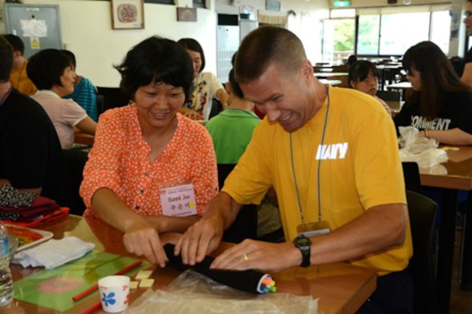 KOJE ISLAND, Republic of Korea (August 24, 2014) Cmdr. Erik Karlson, from Commander, U.S. Naval Forces Korea, practices making gimbop, a traditional Korean snack food, with help from a resident as part of the lunch preparation during a U.S. Navy visit designed to build relationships with the community at Aikwangwon, a home and school for the mentally and physically disabled, on Koje Island, Republic of Korea, August 24. (U.S. Navy photo by Chief Mass Communication Specialist Wendy Wyman/Released) 