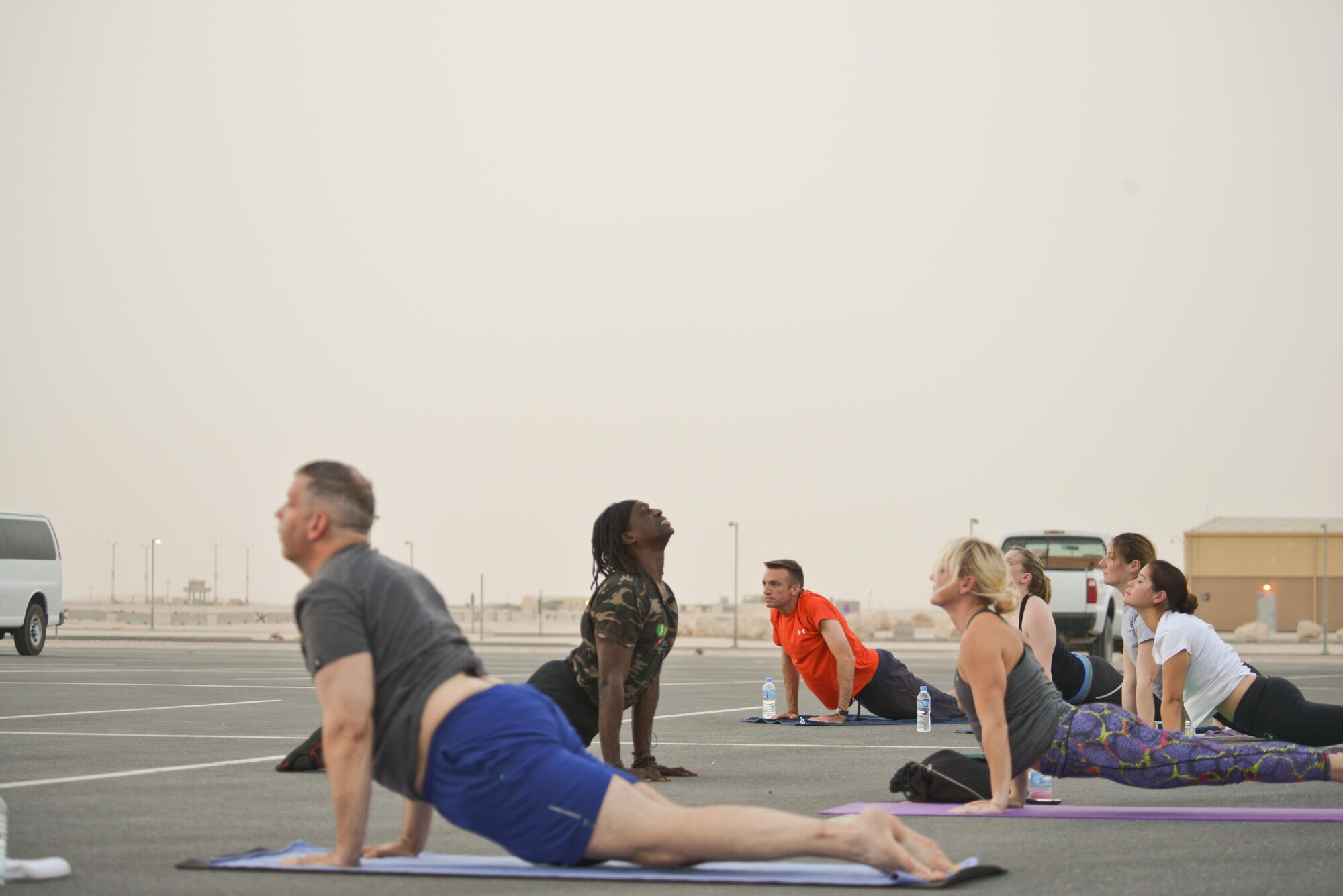 Tracy English, 609th Air and Space Operations Center historian, leads deployed members into the cobra position during the largest Yoga session to take place in Qatar history July 11, 2015 Al Udeid Air Base, Qatar. Tracy English and a few of the other yogis deployed to Al Udeid put together a power yoga routine and introduced it to the base during the largest yoga session in Qatar to date. (U.S. Air Force photo/Staff Sgt. Alexandre Montes)  
