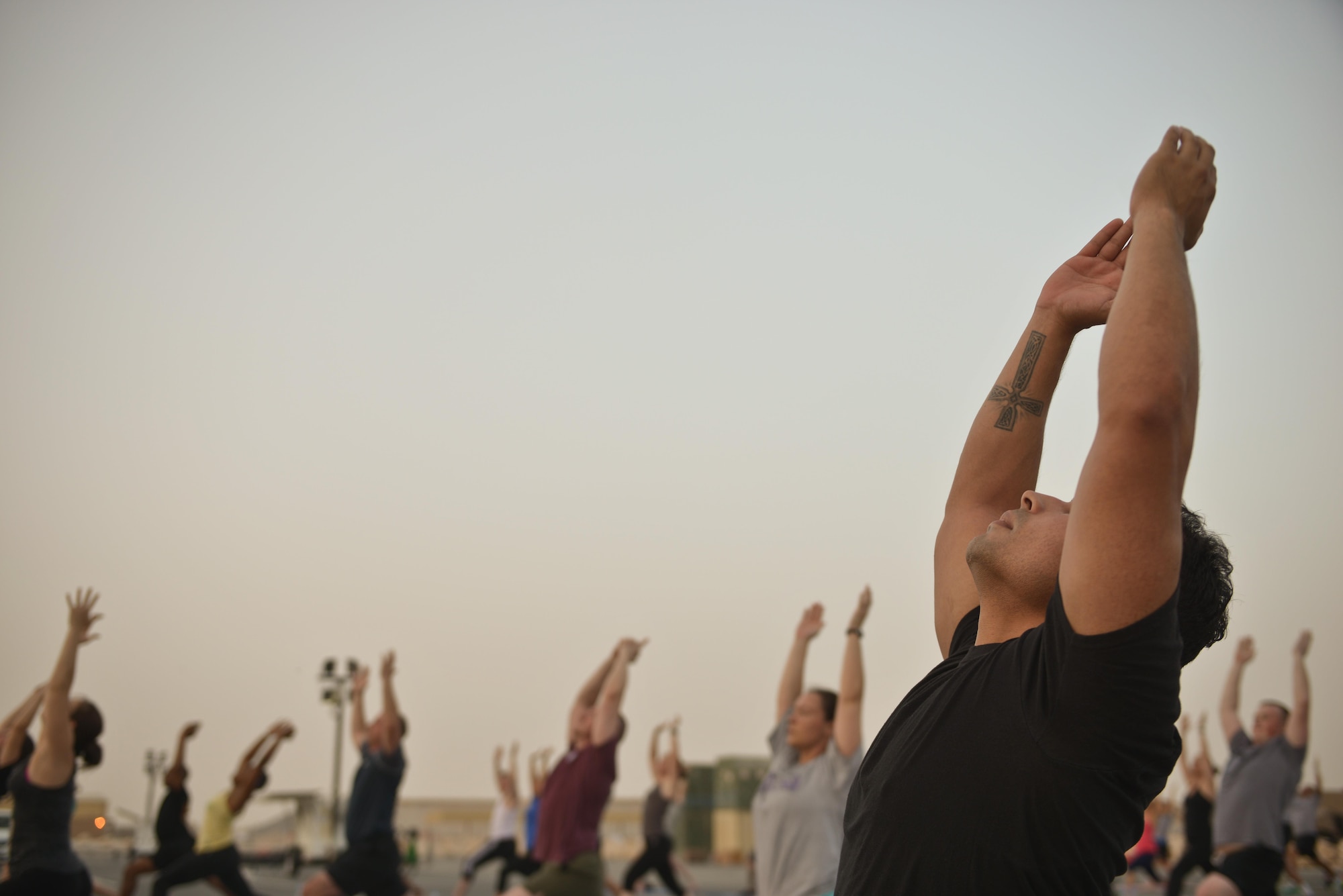 Deployed Soldiers, sailors, airmen, marines, coalition partners and civilians go into the Warrior One pose during the largest Yoga session to take place in Qatar history July 11, 2015 Al Udeid Air Base, Qatar. This event opened its doors to all levels of practitioners from novice to expert. It allowed the fine men and women assigned to Al Udeid Air Base to relax and enjoy a different kind of exercise in a neutral environment. (U.S. Air Force photo/Staff Sgt. Alexandre Montes)
