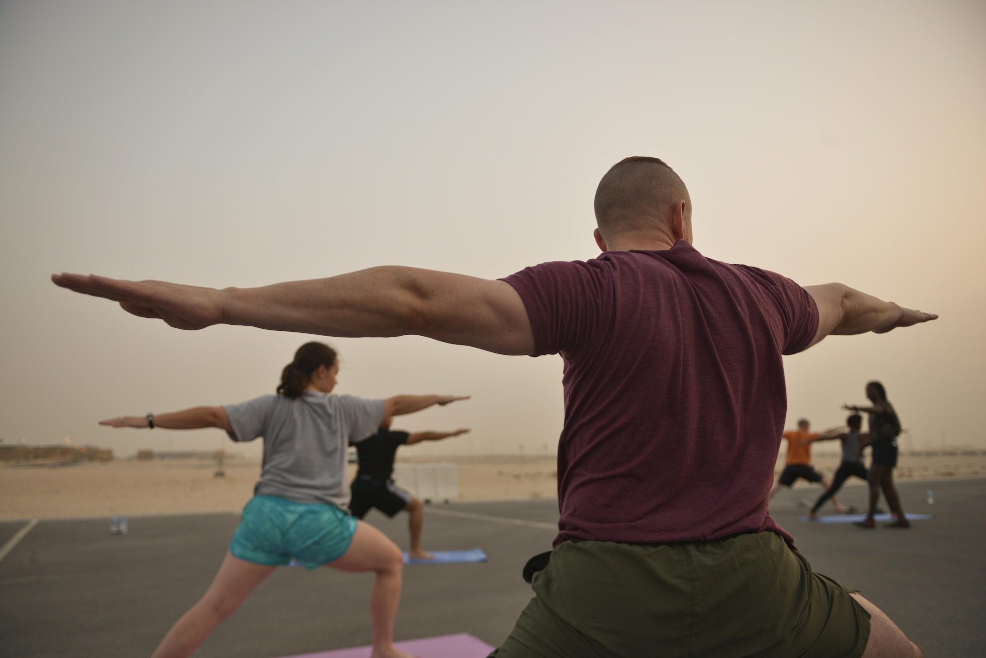Deployed Soldiers, sailors, airmen, marines, coalition partners and civilians go into the Warrior Two pose during the largest Yoga session to take place in Qatar history July 11, 2015 Al Udeid Air Base, Qatar. This event opened its doors to all levels of practitioners from novice to expert. It allowed the fine men and women assigned to Al Udeid Air Base to relax and enjoy a different kind of exercise in a neutral environment. (U.S. Air Force photo/Staff Sgt. Alexandre Montes)