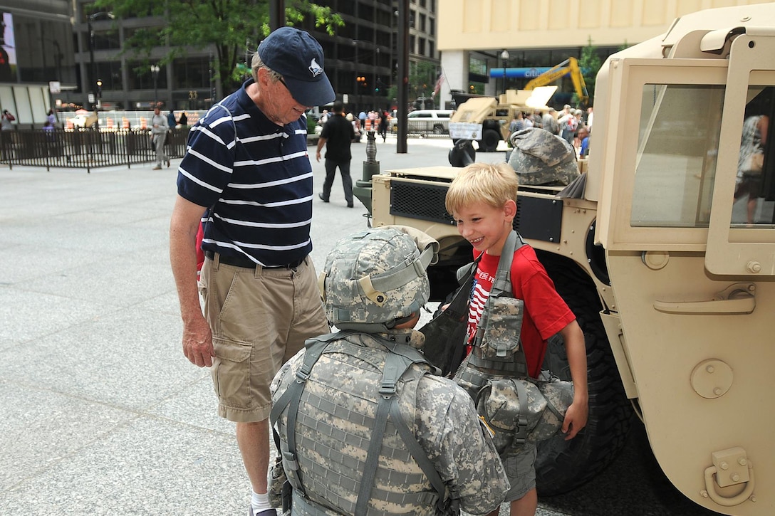 Sgt. 1st Class Anthony L. Taylor, 85th Support Command, assists a boy try on an Army load bearing vest during the U.S. Army’s 240th birthday celebration in downtown Chicago, June 10. The four-hour ceremony included soldiers from throughout the Chicago land area, Junior Reserve Officers’ Training Corps cadets, and Illinois Army National Guard Brig. Gen. Michael Zerbonia as the senior Army representative. (U.S. Army photo by Sgt. Aaron Berogan/Released)