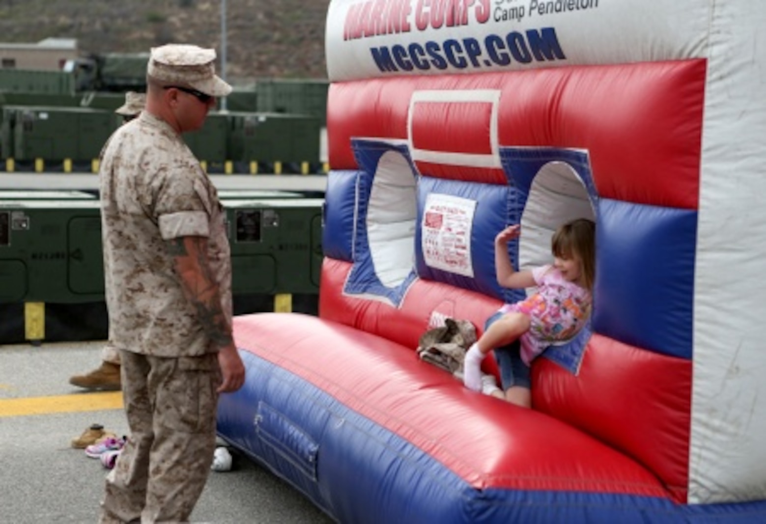 Gunnery Sgt. Jeremy Thrane, platoon sergeant, 7th Engineer Support Battalion, 1st Marine Logistics Group, gets called into a bouncy house by his daughter, Elleanna, at a family day celebration for Marines and Sailors of 7th ESB aboard Camp Pendleton, Calif., July 10, 2015. Included in the celebration were bouncy houses and displays that allowed them to look at things like sniper rifles, armored vehicles and Explosive Ordnance Disposal gear.