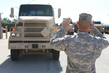 Spc. Shane Brankley, a reservist with the 353rd Transportation Company and Bloomington, Minn., native, guides a fellow reservist to a staging area, July 13. The Soldiers of the 353rd TC are on their way to Camp Roberts, Calif., as part of Nationwide Move 15. The 353rd Transportation Company's westward trek will not only provide training for its Soldiers, but also practical logistics support to its sister unit, the 322nd Maintenance Company, which will be conducting its annual training in California. (U.S. Army photo by Sgt. Victor Ayala, 210th MPAD)