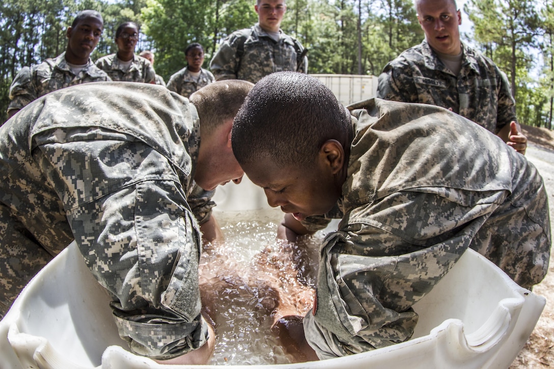 Soldiers with A Company, 3rd Battalion, 13th Infantry Regiment, submerge their arms in ice water for a few seconds to cool down after competing the final hurdle of the endurance obstacle course during their second week of Basic Combat Training at Fort Jackson, S.C. (U.S. Army photo by Sgt. 1st Class Brian Hamilton)