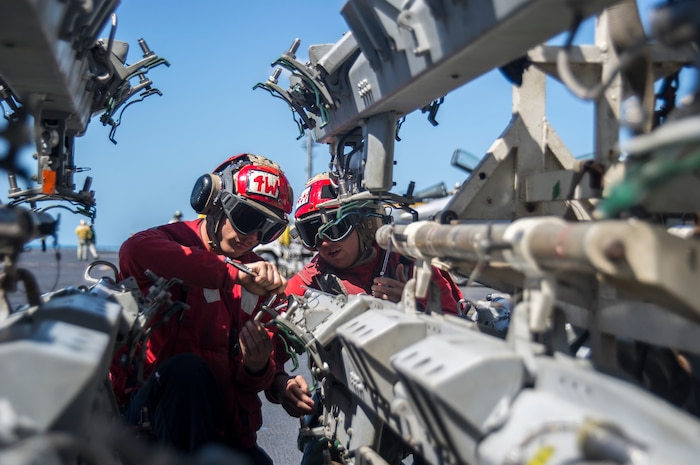 TIMOR SEA (July 15, 2015) - Aviation Ordnanceman Airman Tyler Lazor, from Defanice, Penn., and Aviation Ordnanceman 2nd Class Donald Collins, from Tucson, Ariz., prepare bomb racks for loading on the flight deck of the Nimitz-class aircraft carrier USS George Washington (CVN 73) as part of Talisman Sabre 2015. Talisman Sabre is a biennial exercise that provides an invaluable opportunity for nearly 30,000 U.S. and Australian Defense Force personnel to conduct operations in a combined, joint and interagency environment that will increase both countries' ability to plan and execute a full range of operations from combat missions to humanitarian assistance efforts. 