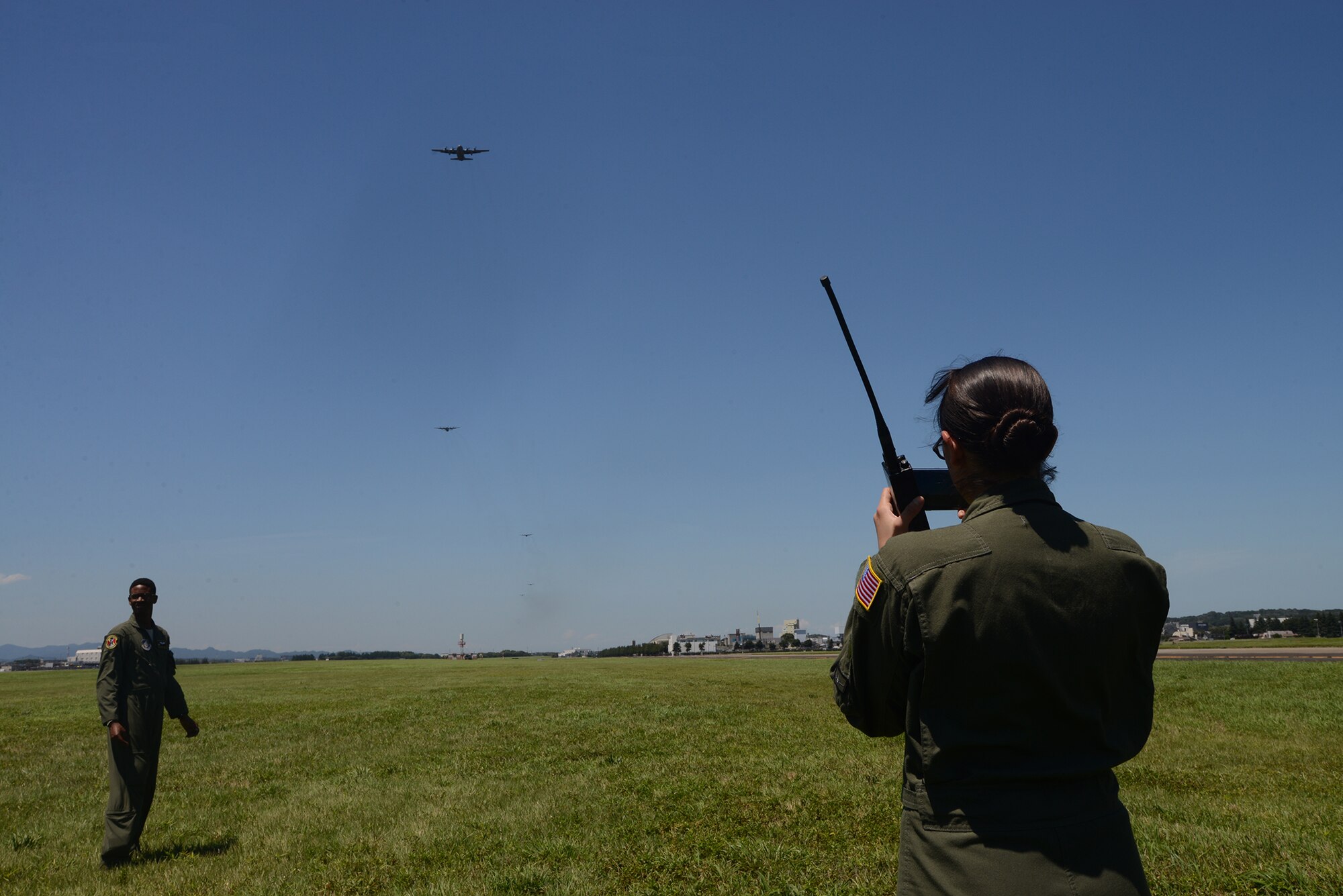 U.S. Air Force Airmen from the 36th Airlift Squadron track bundles dropped from U.S. Air Force C-130 Hercules during large formation training at Yokota Air Base, Japan, July 14, 2015. Nine C-130s participated in training that tested the squadron's ability to accurately drop cargo to a specific target and fly large formation airlift operations. (U.S. Air Force photo by Airman 1st Class David C. Danford/Released)
