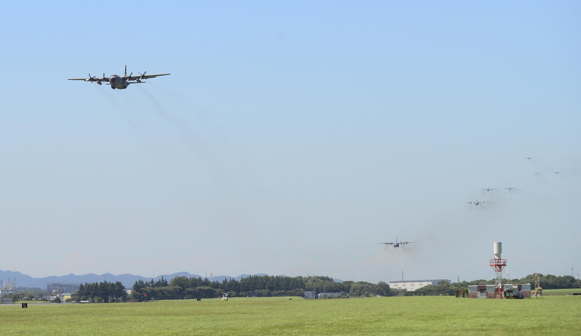 Multiple U.S. Air Force C-130 Hercules aircraft fly over the airfield during a training exercise, Yokota Air Base, Japan, July 14, 2015.. Ten C-130s participated in the exercise which tested the 36th Airlift Squadron’s ability to perform large formation flights. (U.S. Air Force photo by Senior Airman David Owsianka/Released)