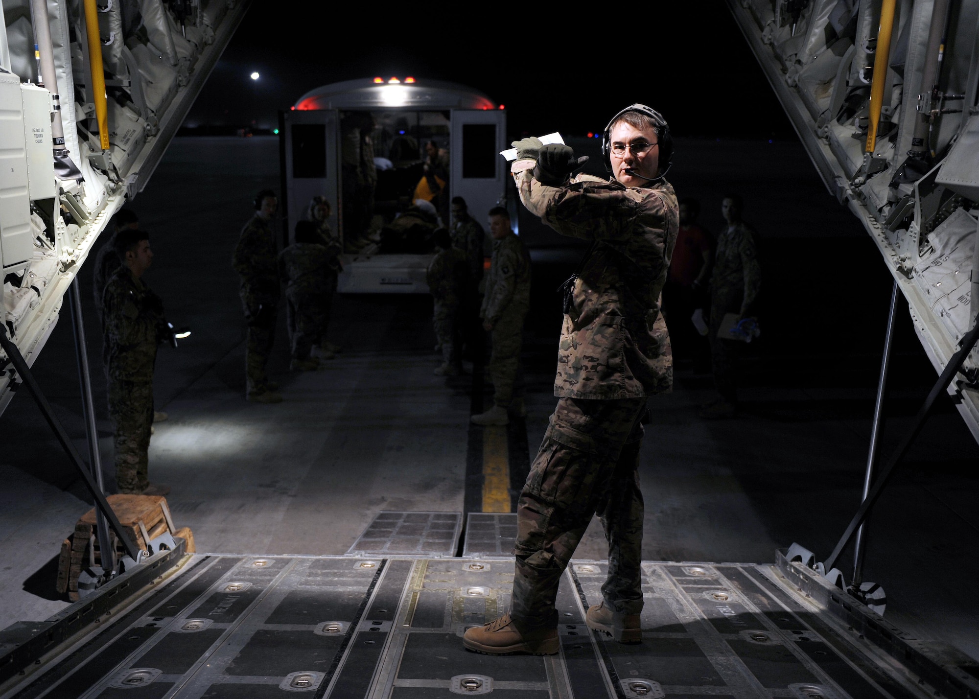 U.S. Air Force Maj. Fred Pounds, 455th Expeditionary Aeromedical Evacuation Squadron flight nurse, communicates with a litter team using hand signals during an AE mission April 19, 2015 at Kandahar Airfield, Afghanistan. 455 EAES Airmen are charged with the responsibility of evacuating the sick and wounded from Central Command to higher echelons of medical care. (U.S. Air Force photo by Staff Sgt. Whitney Amstutz/released)